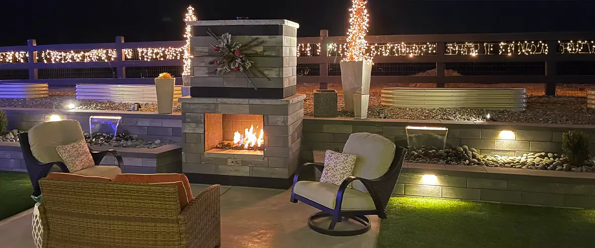 Outdoor fireplace with cozy seating and decorative lights in a modern backyard setting, designed by Easy Green Landscaping.