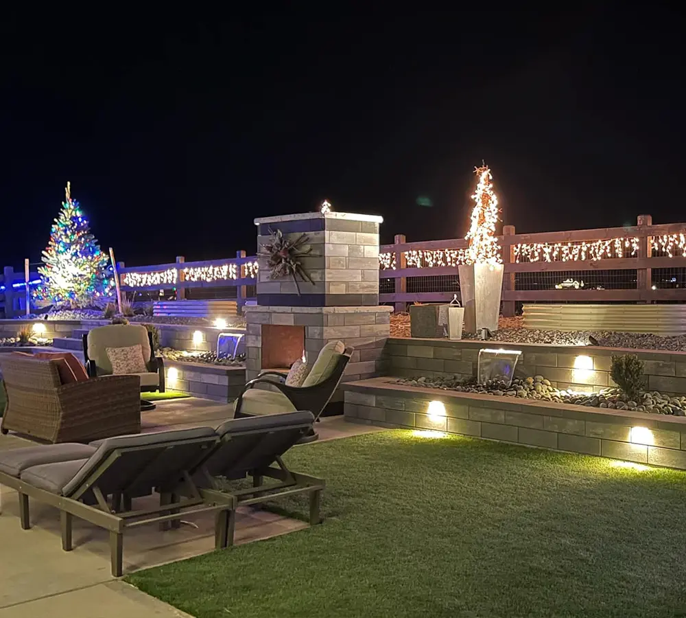 Outdoor patio with festive holiday lighting, fireplace, and cozy seating area for evening gatherings.