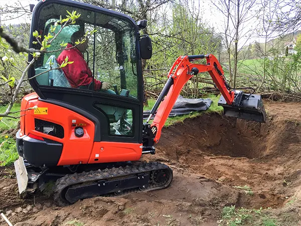 Excavator digging a backyard pond, preparing for a custom water feature installation.