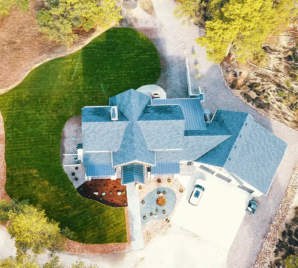 Aerial view of landscaped yard surrounding a modern home with green lawn