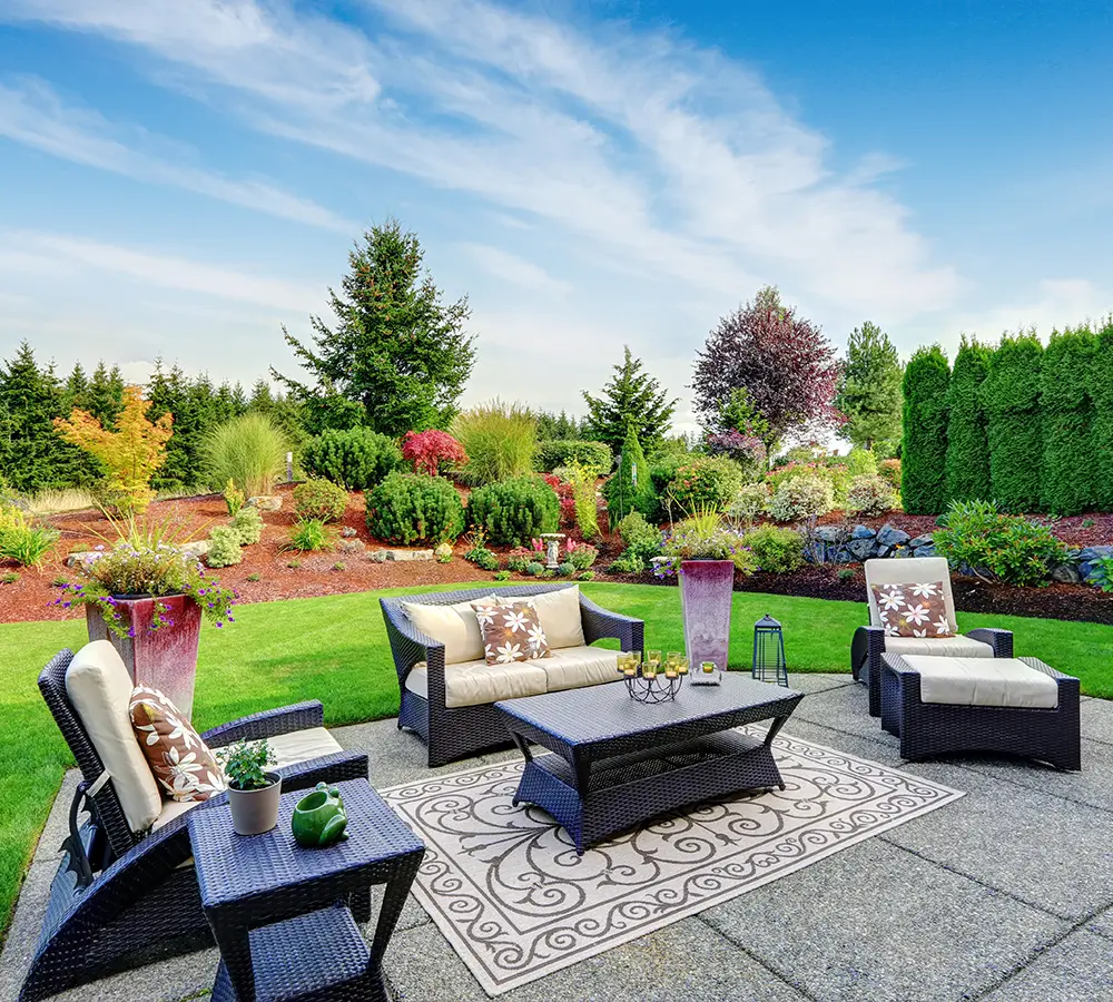 Elegant garden seating area with colorful landscaping and plush chairs.