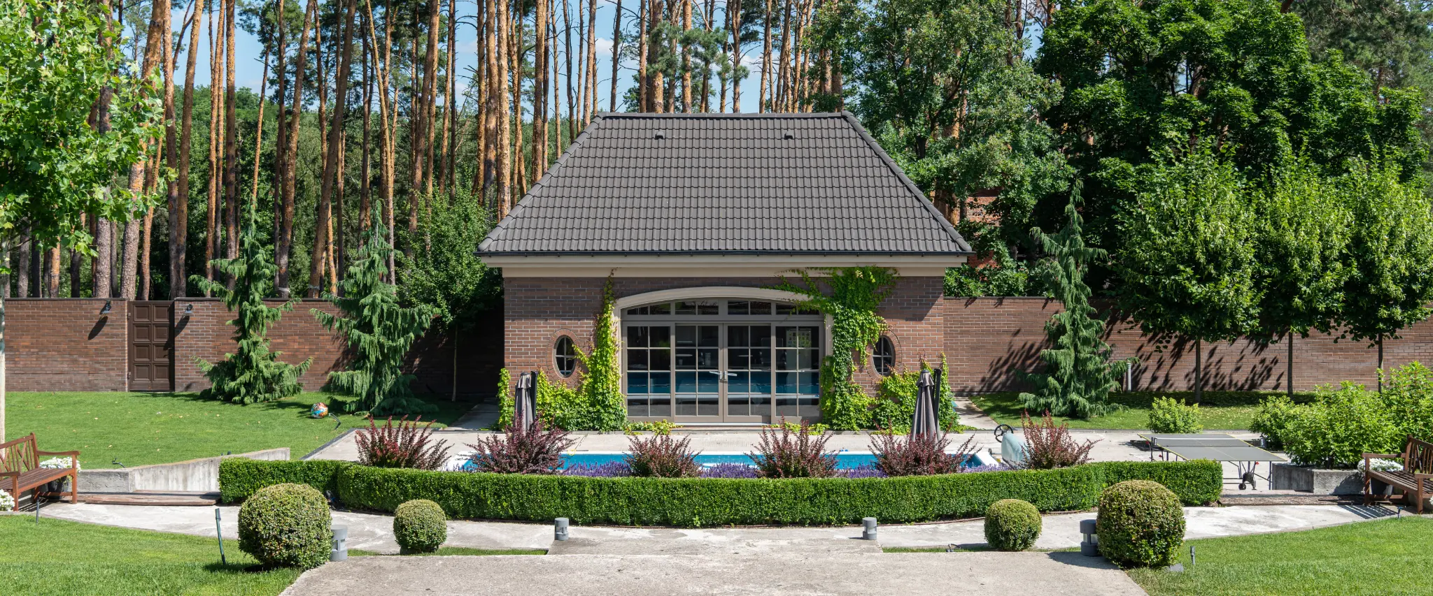 A luxury garden featuring a private pool, brick fencing, and neatly manicured greenery for a serene outdoor space.