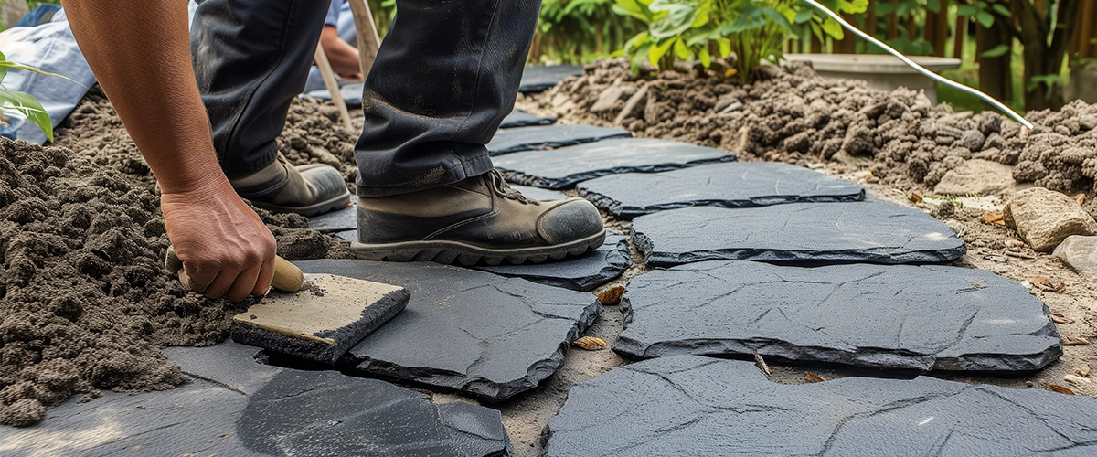 professional landscaper laying textured slabs for a garden path